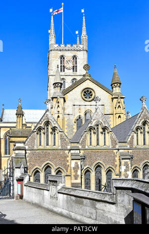 London street scene della chiesa di Inghilterra orientale esterno anteriore & tower con bandiera a Southwark Cathedral & passerella link a Borough High Street England Regno Unito Foto Stock