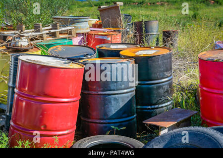 Una colorata collezione delle importazioni oggetto di dumping, vecchio, i fusti di olio in un campo di gomme vecchie e arrugginite junk, creando un apparentemente sito pericolosi Foto Stock