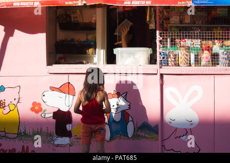 Giovane ragazza filippina Acquisto di ghiaccio a un tradizionale Negozio convenienza dipinto di rosa. Questi sono noti come sari sari negozi, a Cebu City - Filippine Foto Stock