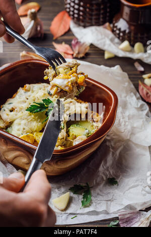 Patate al forno con carne immerso nel formaggio in argilla piatti marrone su un sfondo di legno. Foto Stock