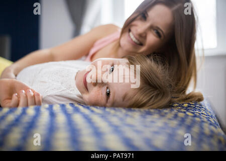 Felice madre e figlia giacente sul letto Foto Stock