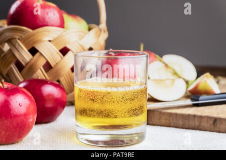 Close-up di immagine cidre bere e mature mele succose su tavola in legno rustico. Bicchiere di fatto in casa e sidro coltivati localmente mele biologiche Foto Stock