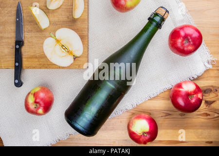 Lay piatto con gelido raffreddata corked cidre bottiglia su tavola in legno rustico. Vista superiore del premio il sidro di mele e di coltivati localmente mele biologiche Foto Stock