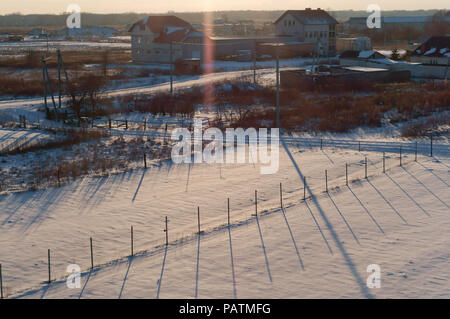 Paesaggio rurale in inverno, lunghe ombre nella neve al tramonto Foto Stock