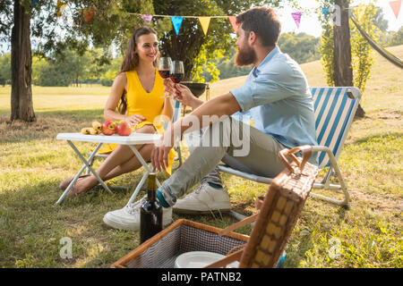 Bella giovane in amore la tostatura con un bicchiere di vino rosso durante il picnic romantico Foto Stock