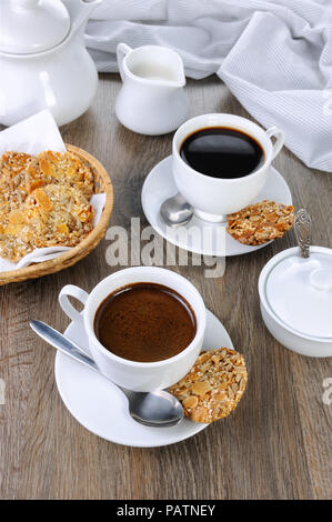 Una tazza di caffè con senza glutine cookies da cereali sul tavolo da caffè. Si tratta di tempo hanno un morso Foto Stock