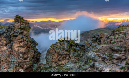 Una nuvola che sta per oscurare il sole alle spalle di roccia tagliata al tramonto sulla Trail Ridge Road nel Parco Nazionale delle Montagne Rocciose, Colorado. Foto Stock