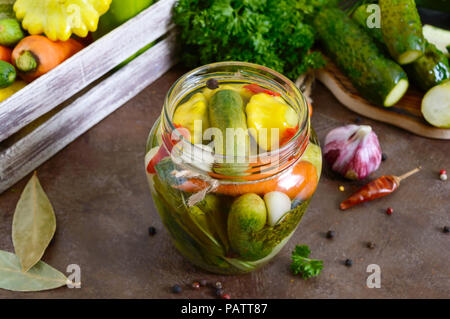 Verdure marinate in un vasetto di vetro. Un assortimento di cetrioli, peperoni, carote, patissons, zucchine. Pickles. Foto Stock