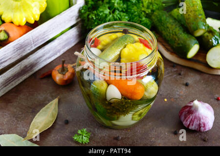 Verdure marinate in un vasetto di vetro. Un assortimento di cetrioli, peperoni, carote, patissons, zucchine. Pickles. Foto Stock