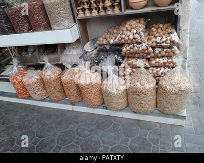 Gamberi secchi in buste trasparenti e con la buccia le noci in pacchetti, spezie in confezioni trasparenti in piedi sul contatore nel mercato in Deira, Dubai. Foto Stock