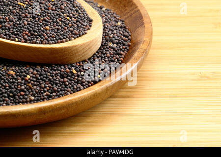 Nero Semi di senape su uno sfondo di legno Foto Stock