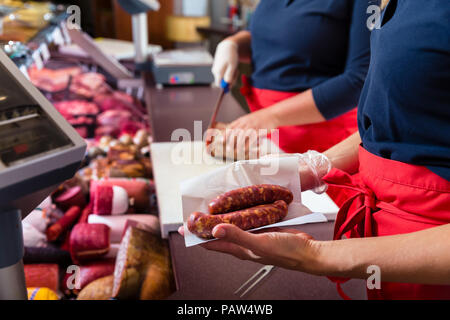 Le donne di vendite nel negozio di macellaio la vendita di carne e salumi Foto Stock