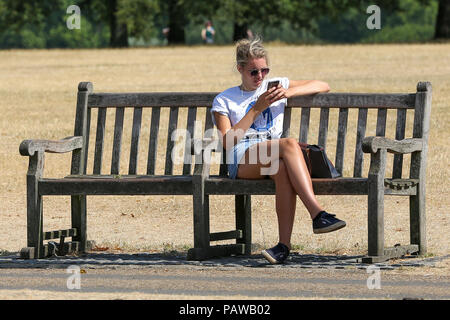 Hyde Park. Londra. Regno Unito 25 luglio 2018 - Una donna seduta su una panchina nel parco in Hyde Park su un molto caldi e umidi giorni nella capitale. Secondo il Met Office la temperatura a Londra e il Sud Est rischia di raggiungere 35 gradi celsius giovedì. Credito: Dinendra Haria/Alamy Live News Foto Stock