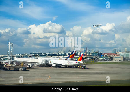 Manila NAIA Airport, Filippine - 28 Novembre 2016: un piano Skyjet prende il largo con un paio di Philippine Airlines aerei lo scarico su asfalto al di sotto. Foto Stock