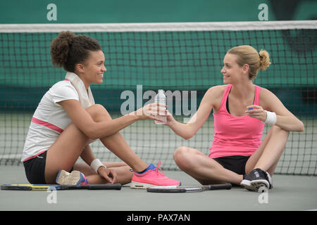 Due belle ragazze seduta vicino net presso il campo da tennis Foto Stock