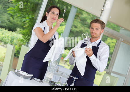 I camerieri impostazione delle tabelle alla gastronomia il ristorante Foto Stock