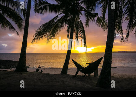Sunset silhouette dell uomo di bere il rum sul Guyam tropicale isola, parte di Siargao, Mindanao - Filippine Foto Stock