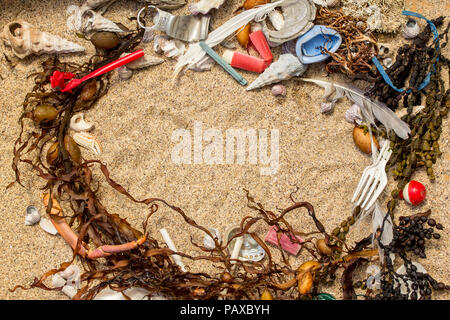 Plastica reale inquinamento che si trova sulla spiaggia in mista con alghe marine naturali e conchiglie dove è stato trovato lo spazio per il testo Foto Stock