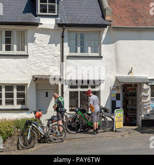 Drewsteignton, Devon, Inghilterra, Regno Unito. Cylists prendere una pausa presso il negozio del villaggio per rinfreschi, Foto Stock