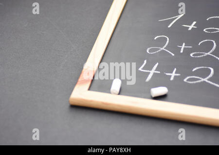 Frammento di lavagna nera con la scritta a mano semplici equazioni matematiche rotti gessi bianchi. Si torna a scuola il concetto di apprendimento dell'istruzione. I Creative Foto Stock