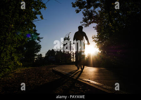 Immagine del ciclista che indossa il casco equitazione intorno città in serata Foto Stock