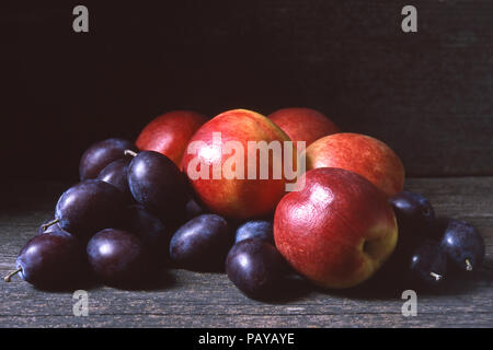 Fresche le pesche noci e le prugne o damsons al buio su un sfondo di legno, copia o spazio di testo Foto Stock