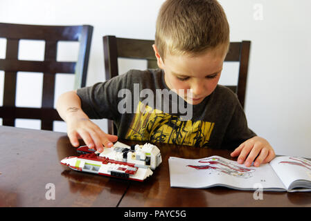 Un giovane ragazzo (6 yr old) concentrando la sua Lego Star Wars fighter Foto Stock