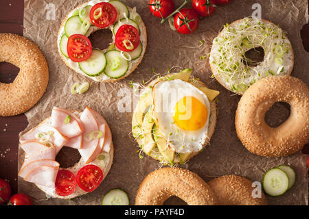 Varietà di panini su bagel: uovo, avocado, prosciutto, pomodoro, formaggio a pasta morbida, di germogli alfalfa Foto Stock