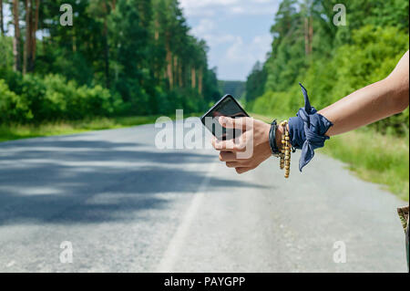 Adolescente mano con lo smartphone autostop per il concetto di viaggio. In primo piano Foto Stock