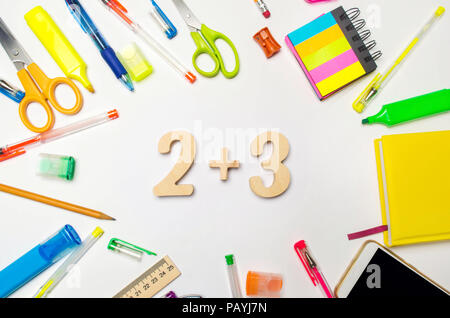 Matematica. numeri 2 plus 3 sul banco di scuola. concetto di istruzione. torna a scuola. articoli di cancelleria. Sfondo bianco. adesivi colorati, penne, matite, Foto Stock