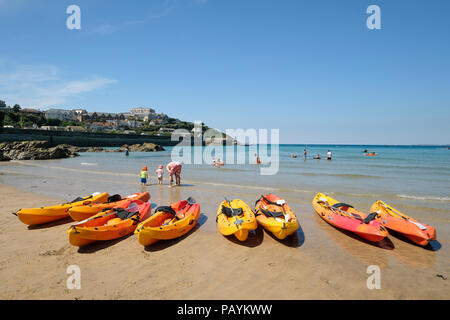 Una fila di vivacemente colorato Canoe sulla spiaggia a Newquay in Cornovaglia Foto Stock