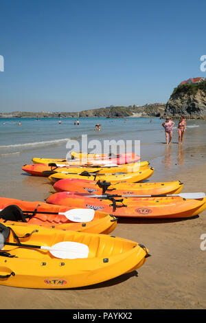 Una fila di vivacemente colorato Canoe sulla spiaggia a Newquay in Cornovaglia Foto Stock