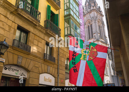 Bilbao street, vista di un basco (Euskadi) bandiera recante una stemma comunale appeso nel centro del Casco Viejo (Città Vecchia) zona di Bilbao. Foto Stock