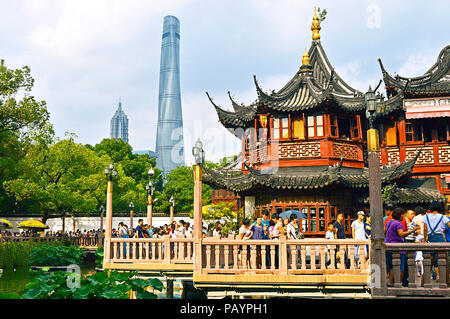 Shanghai, Cina, luglio 2015. La gente che camminava sul ponte Jiuqu nel Giardino di Yu Shanghai in una giornata di sole. L' Yuyuan Tea House e grattacieli in background. Foto Stock