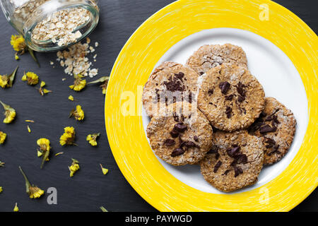 Farina di avena biscotti al cioccolato su una piastra di colore giallo Foto Stock