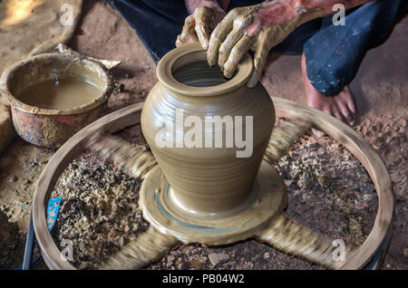 Vista dettagliata del potter mani rendendo argilla pentola di acqua sulla ruota di ceramiche. Pentole di creta sono utilizzate fin dai tempi antichi e può essere trovato nel subcontinente indiano. Foto Stock