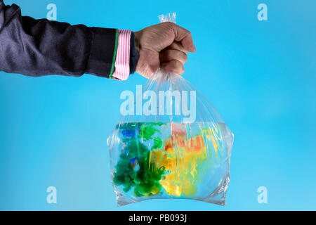 Mano d'uomo tenendo un sacchetto di plastica riempito di acqua e vernice acrilica Foto Stock