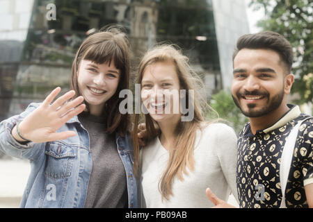 Tre amici in città in piedi a fianco a fianco Foto Stock