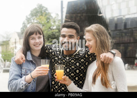 Tre amici sorridente facendo un brindisi celebrativo Foto Stock