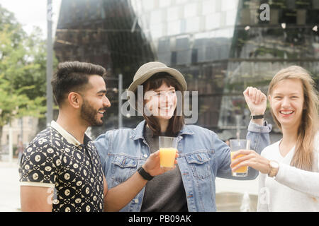 Tre amici sorridente facendo un brindisi celebrativo Foto Stock