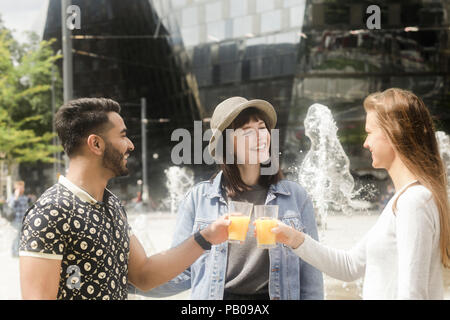 Tre amici sorridente facendo un brindisi celebrativo Foto Stock