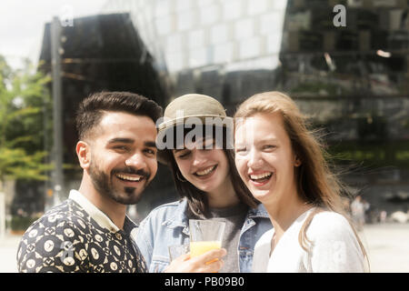 Tre amici sorridente facendo un brindisi celebrativo Foto Stock