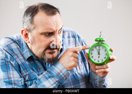 Ritratto di uomo in possesso di un orologio che mostra da cinque a dodici tempo Foto Stock