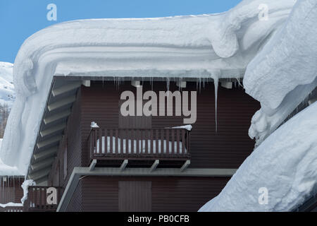 Il tetto della casa sotto uno spesso strato di neve Foto Stock