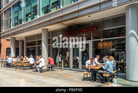 I clienti seduti fuori e dentro l'Unione Pizza ristorante pizzeria in una calda giornata estiva in Spitalfield, London, England, Regno Unito Foto Stock