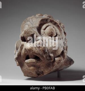 Testa di una grottesca. Cultura: francese. Dimensioni: complessivo: 14 x 11 3/4 x 13 3/4 in. (35,6 x 29,8 x 34,9 cm) 82lb. (37.2kg). Data: ca. 1200-1220. L'effetto comico del muttonchop whiskers, naso a bulbo, enormi occhi e bocca aperta di questa testa grottesca dimostra l'estrema espressioni presenti nella scultura marginale. La testa assomiglia ad altri su mensole di supporto del cornicione del tetto di una delle principali chiese di Châlons-sur-Marne. Le funzioni grassetto, parte di un linguaggio visivo specifico di edifici medievali, sono destinate ad essere visto da una distanza. Una recente ricerca suggerisce che tale biz Foto Stock