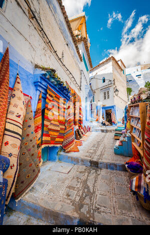 Vicolo stretto, moquette e negozi di artigianato, case blu, medina di Chefchaouen, Chaouen, Tangier-Tétouan, Marocco Foto Stock