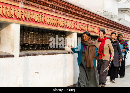 Donne al muro di mani a Swayambhunath o Monkey tempio, rotolando ruote di preghiera, Kathmandu, Nepal Foto Stock