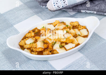 Ristorante delizioso poutine pasto sulla tovaglia pasto canadese fatta con patatine e salsa di cagliata di formaggio Foto Stock