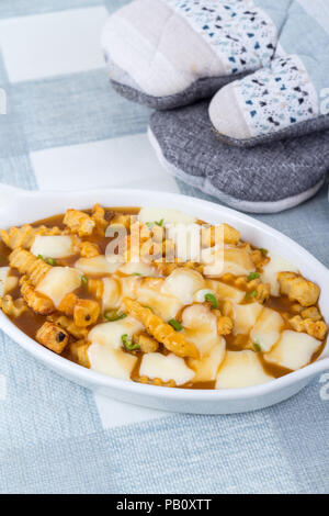 Ristorante delizioso poutine pasto sulla tovaglia pasto canadese fatta con patatine e salsa di cagliata di formaggio Foto Stock